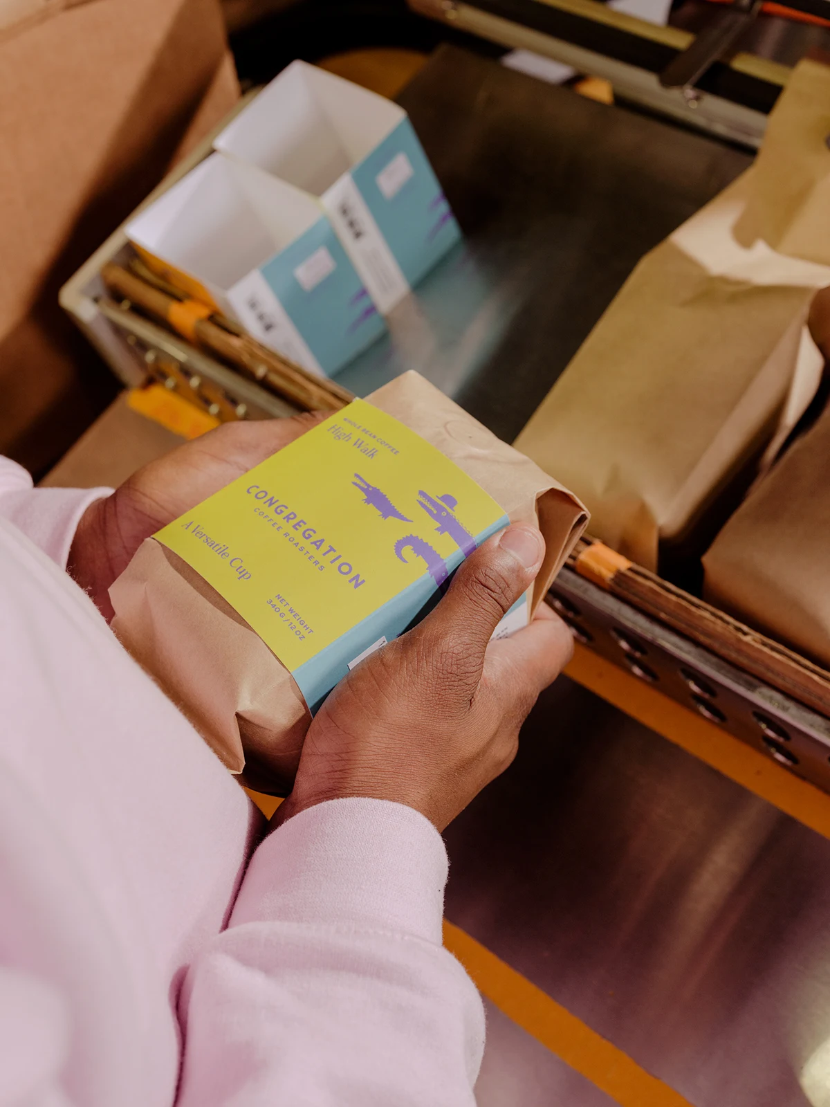 A customer holds a Congregation Coffee bag with its new colorful packaging sleeve